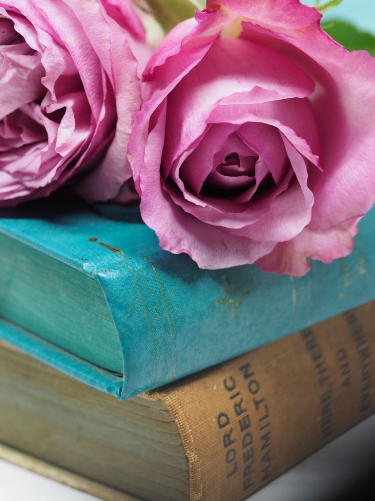 Pink roses resting on a stack of vintage books