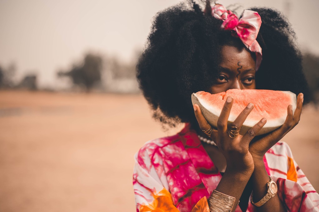 Woman in vibrant tie-dye holding a slice of watermelon, WAYF Journal homepage cover