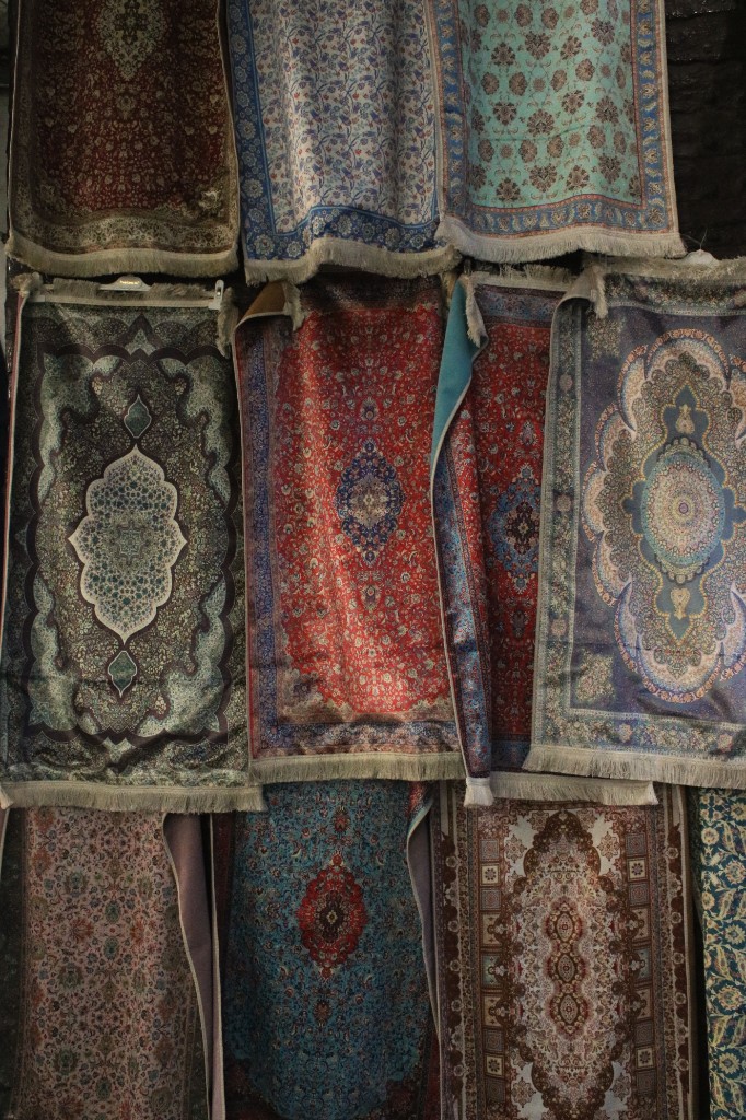 Colorful patterned rugs and textiles hanging on a wall